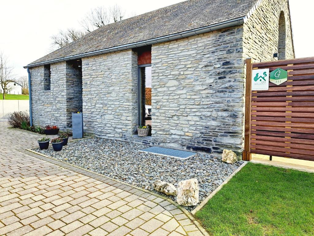 un edificio de piedra con una puerta y un cementerio en Gîte A Brouca en Gouvy