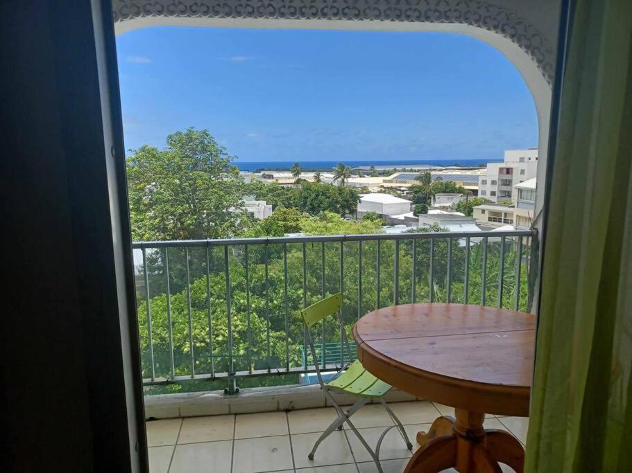 balcón con mesa y vistas al océano en Appartement spacieux, en Sainte-Clotilde