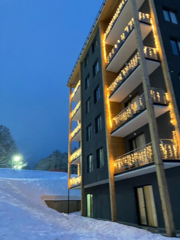a building in the snow with lights on it at Crystal Woods in Bakuriani