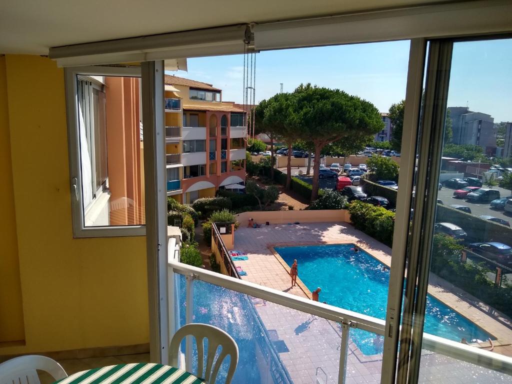 un balcon avec vue sur une piscine dans l'établissement JARDINS DU CAP Joli T2 avec piscine Plage Richelieu Cap d'Agde, au Cap d'Agde
