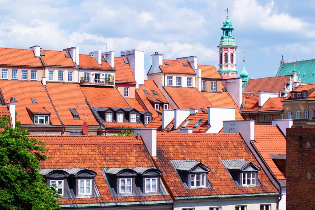 a group of roofs with a clock tower in the background at Podwale str Large flat in the heart of Old Town in Warsaw