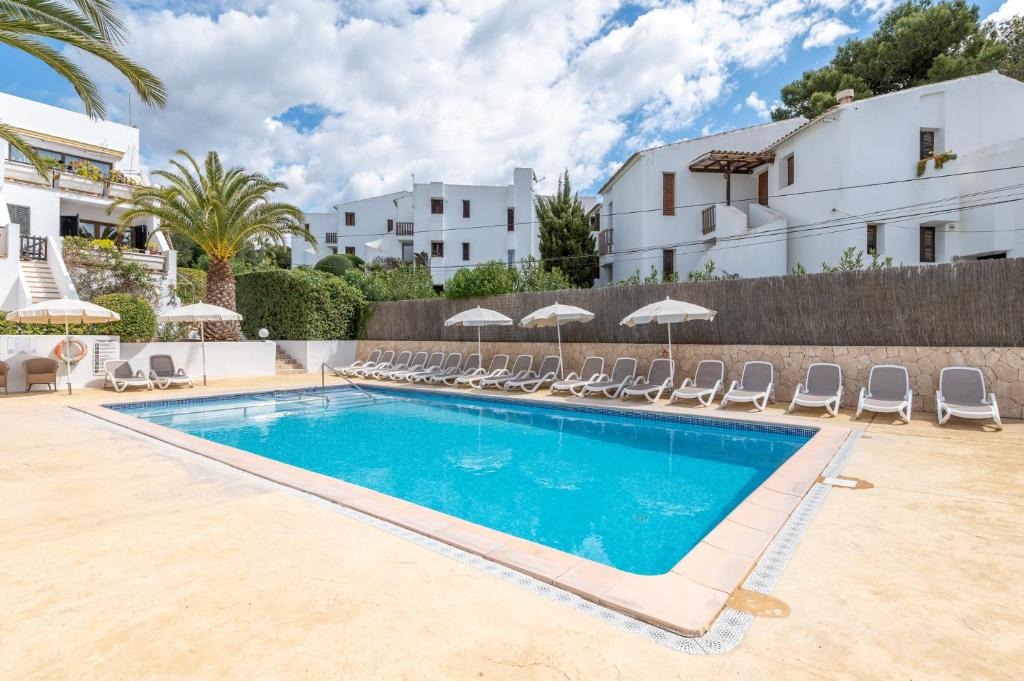 una piscina en una villa con sillas y un edificio en Apartamento Erizo de Mar en Felanitx