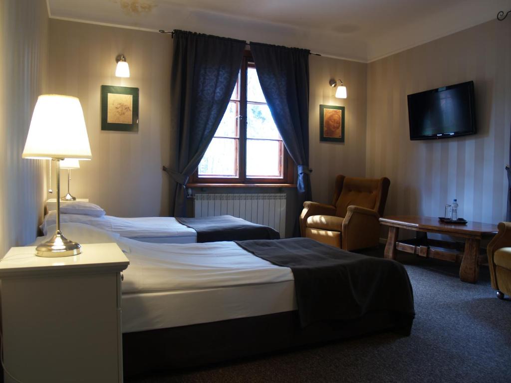 a hotel room with two beds and a television at Leśny Dworek in Wyszk&oacute;w