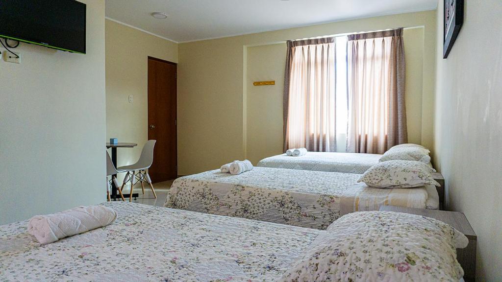 um quarto com 3 camas e uma janela em Las Palmeras Hospedaje & Restaurante em Nuevo Imperial