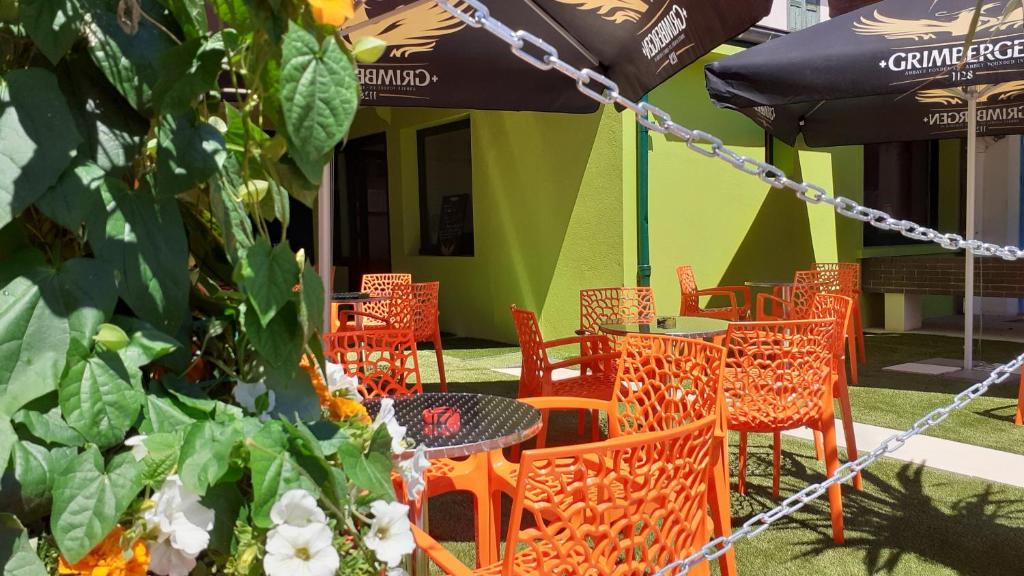ルーアンにあるHOTEL DU JURAのオレンジ色の椅子・テーブル・傘