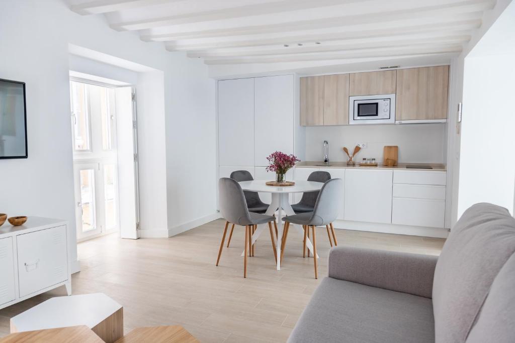 een witte keuken en een eetkamer met een tafel en stoelen bij Villalobos Suites by Luxury Suites Cadíz in Cádiz