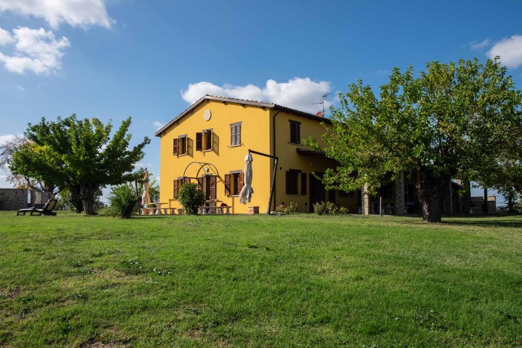 a yellow house in a field of grass at B&B La Casa del Gallese in Sorbolongo