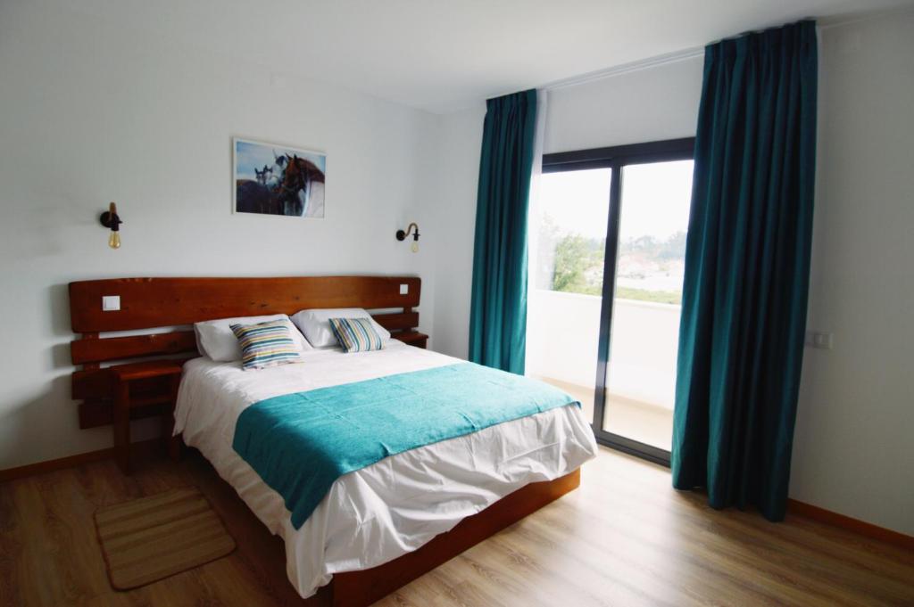 - une chambre avec un lit doté de rideaux bleus et d'une fenêtre dans l'établissement Bed & Breakast EQUITARE RURAL, à Miranda do Corvo