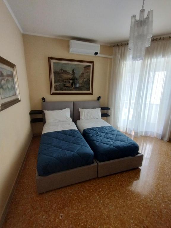 ローマにあるAppartamento Fiore Roma Cinecittàのベッドルーム1室(青いシーツと窓付きのベッド2台付)