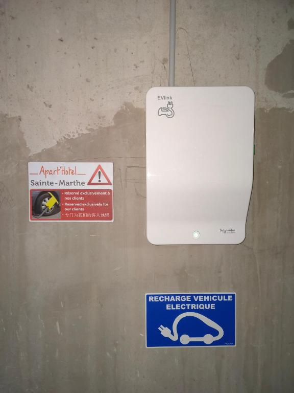 two signs on a wall next to a white appliance at ApartHotel Sainte-Marthe in Avignon