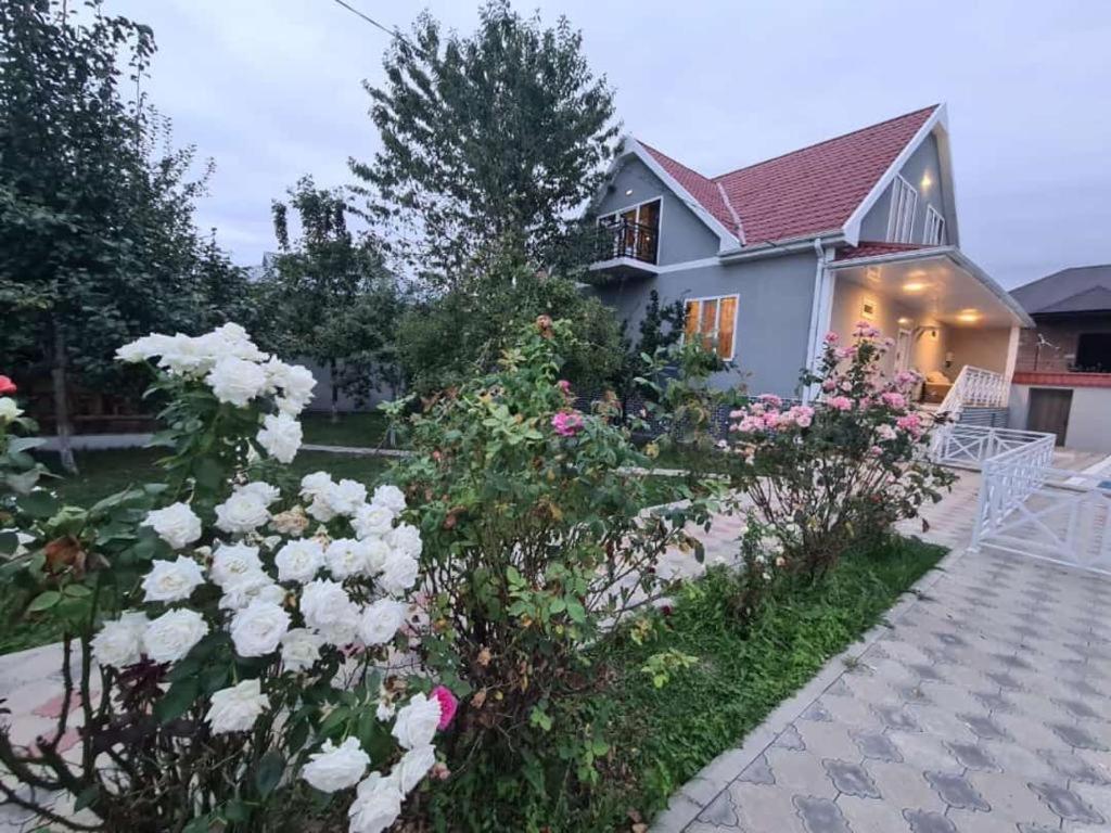 uma casa com um jardim de rosas brancas em ВИЛЛА / VILLA em Gabala