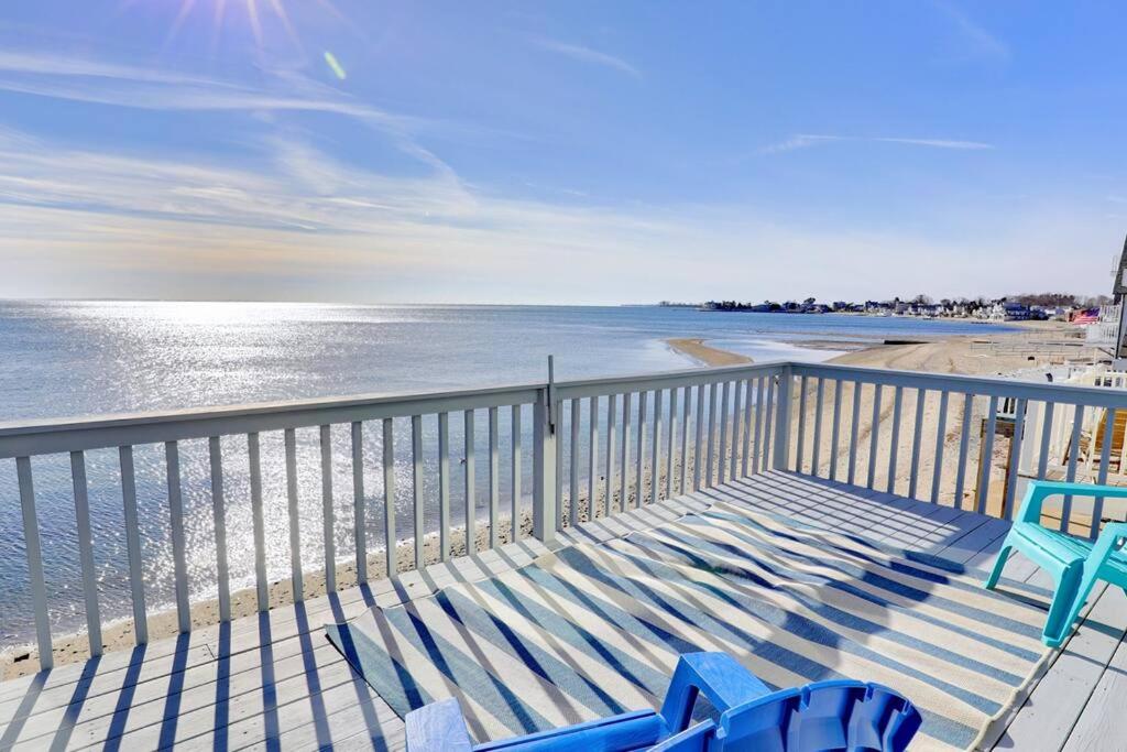 a balcony with two blue chairs and the beach at Cheerful 3 Bedroom Beach Front Cottage with Fire Place in Milford