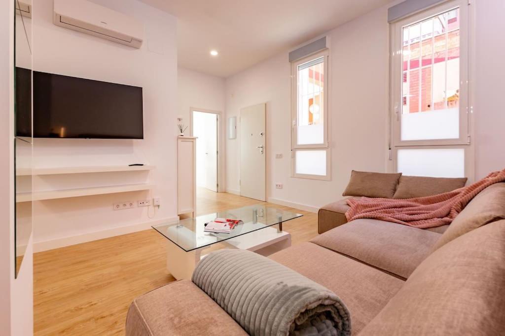 ein Wohnzimmer mit einem Sofa und einem TV in der Unterkunft Elegante y nuevo apartamento junto al Palacio Congresos in Sevilla
