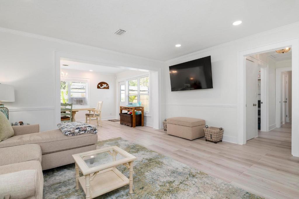 un salon avec un canapé et une télévision sur un mur dans l'établissement Coastal Vibes! Tropical heated pool home short drive to the beach, à Bradenton