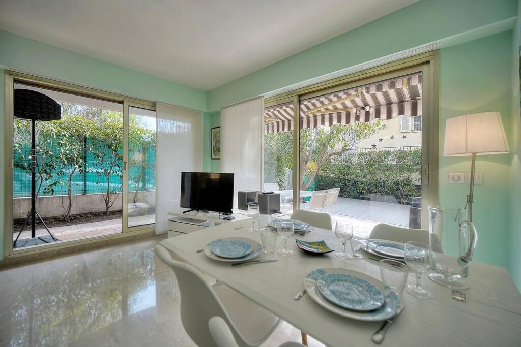 une salle à manger avec une table, des chaises et des fenêtres dans l'établissement Immogroom - Quiet T2 - Garden level - AC - Wifi, à Cannes