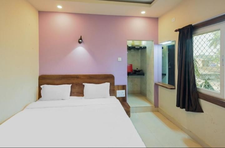 a bedroom with a bed and a pink wall at Hotel basanti in Puri