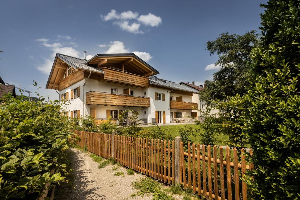 une maison avec une clôture en bois devant elle dans l'établissement Alpin Supreme, à Oberstdorf