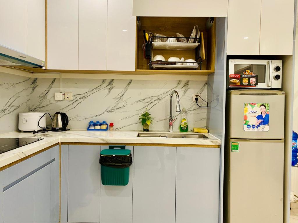  La cuisine est équipée de placards blancs et d'un réfrigérateur. dans l'établissement Vinhomes Grand Park Homestay, à Long Bình