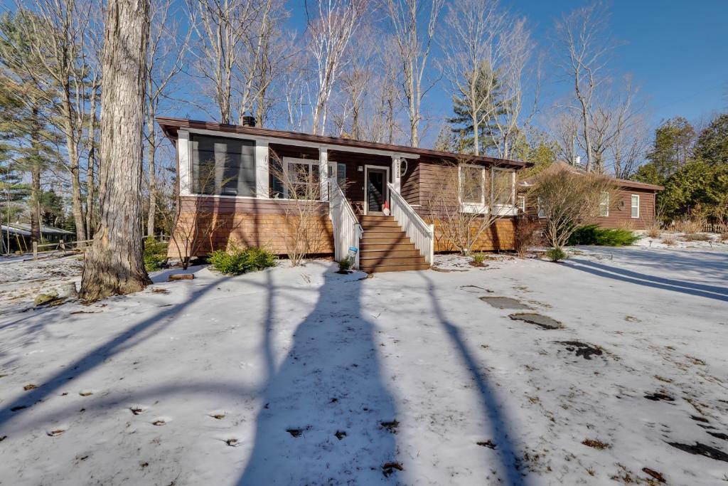 uma casa na neve com uma longa sombra em Pinecone Cabin em Charlevoix
