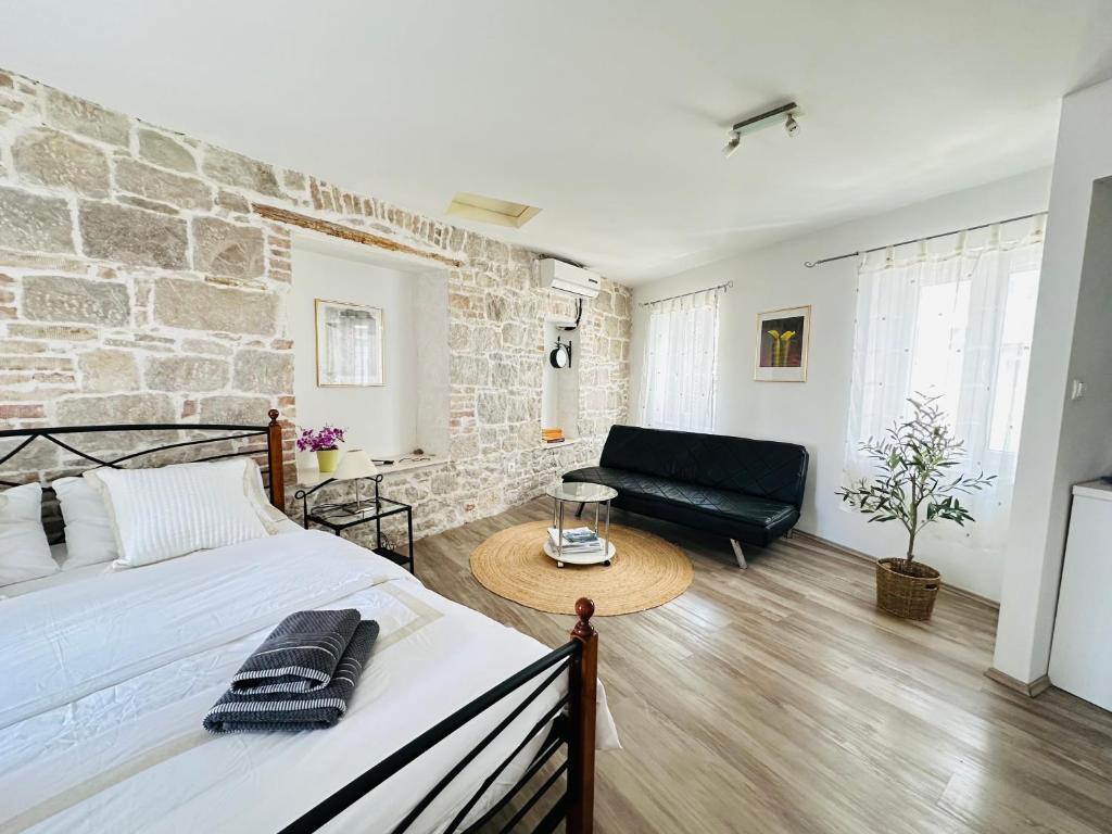 1 dormitorio con cama y pared de ladrillo en Dani Apartments, en Split