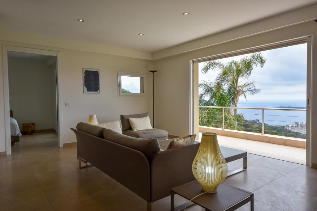 un salon avec un canapé et une grande fenêtre dans l'établissement Clos des Iles, Havre de paix vue mer à 10 minutes du Palais, à Vallauris