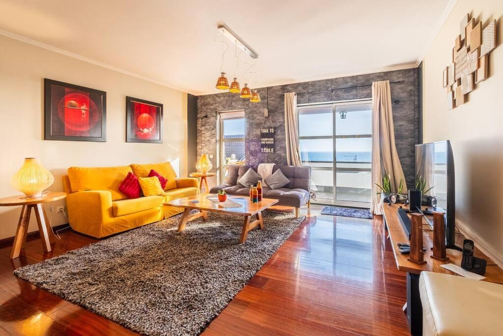 a living room with a yellow couch and a table at Saudades do Sol y Mar Apartment in Lagoa