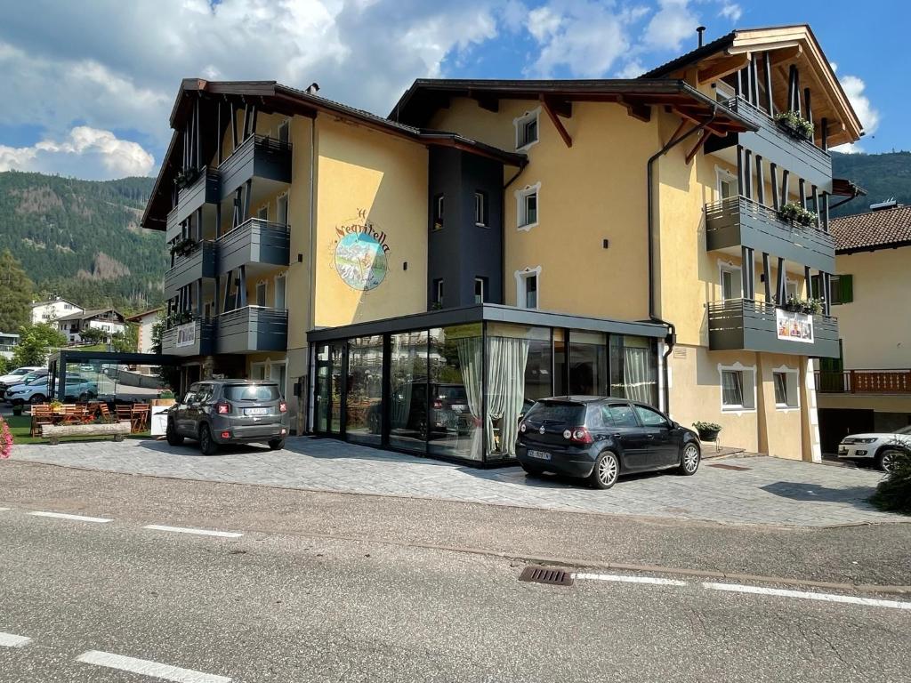 a large building with cars parked in front of it at Albergo Negritella in Ziano di Fiemme