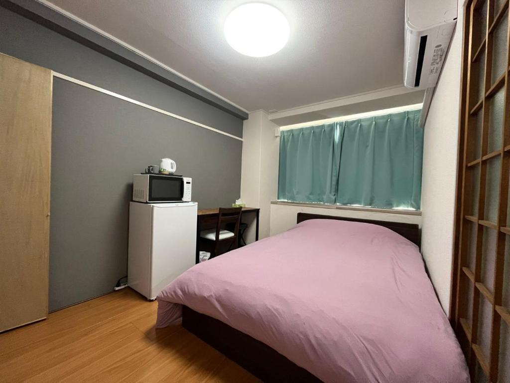 a small bedroom with a bed and a microwave at 玉藻藤塚町 in Takamatsu