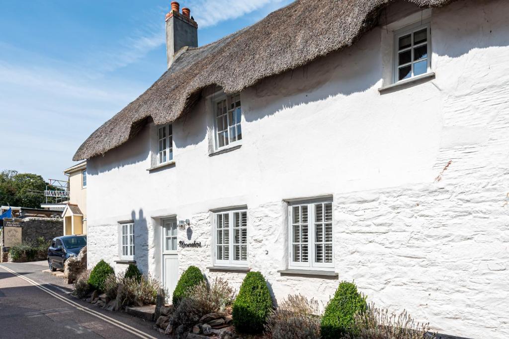 a white cottage with a thatched roof at Moonrakers in Malborough