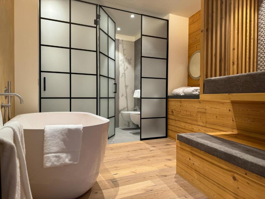 ein Badezimmer mit einer großen Badewanne und einem Waschbecken in der Unterkunft Vivi Suites&Spa Molveno in Molveno