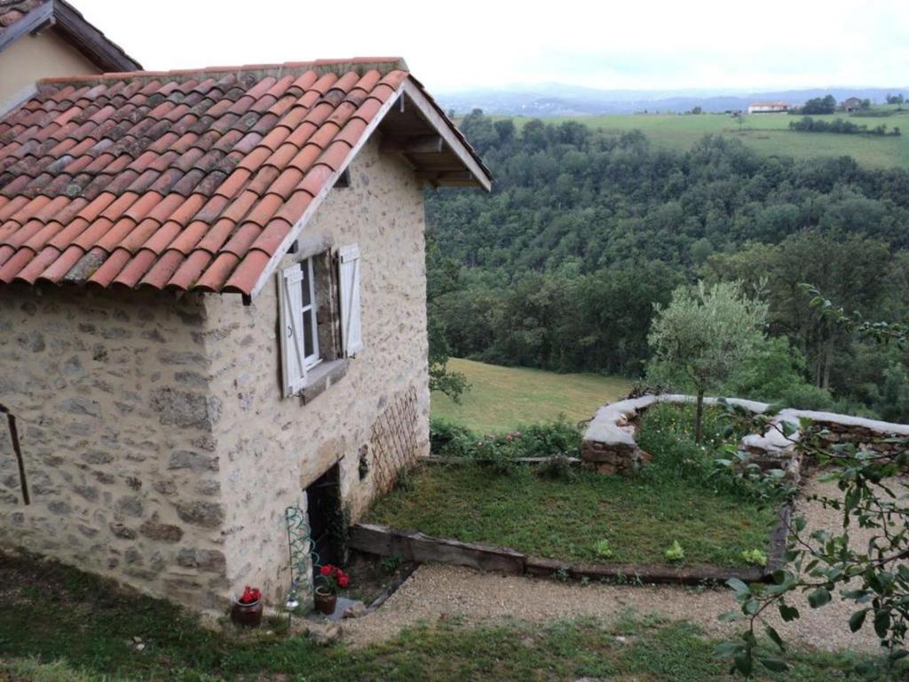 a stone house with a red roof on a hill at Maison En Pierres Proche Agnac in Firmi