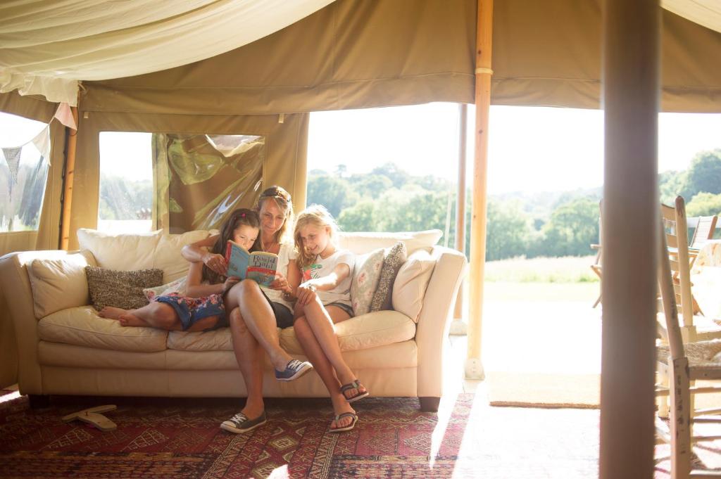 a man and two girls sitting on a couch at Cuckoo Down Farm Glamping in Venn Ottery