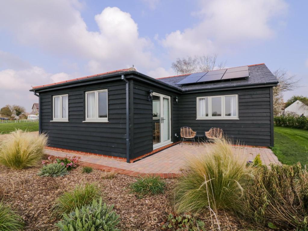 une petite maison noire avec des panneaux solaires dans l'établissement Pippin Cottage, à Clacton-on-Sea