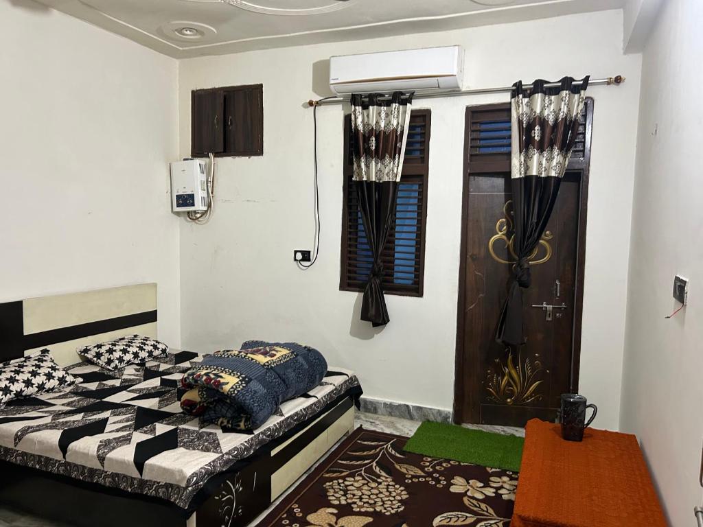 1 dormitorio con cama, ventana y puerta en Family homestay en Vrindāvan