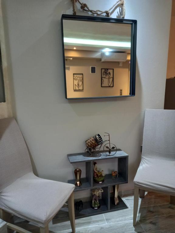 um espelho numa parede com duas cadeiras e uma mesa em AGALI HOUSE em Limenaria