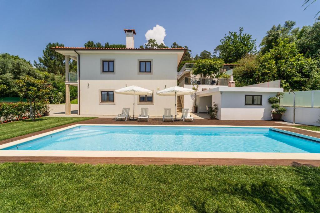 a villa with a swimming pool in front of a house at Casa de Eiró by House and People in Barcelos