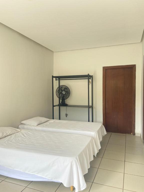 duas camas num quarto branco com uma porta em Villa do Lago em Poços de Caldas