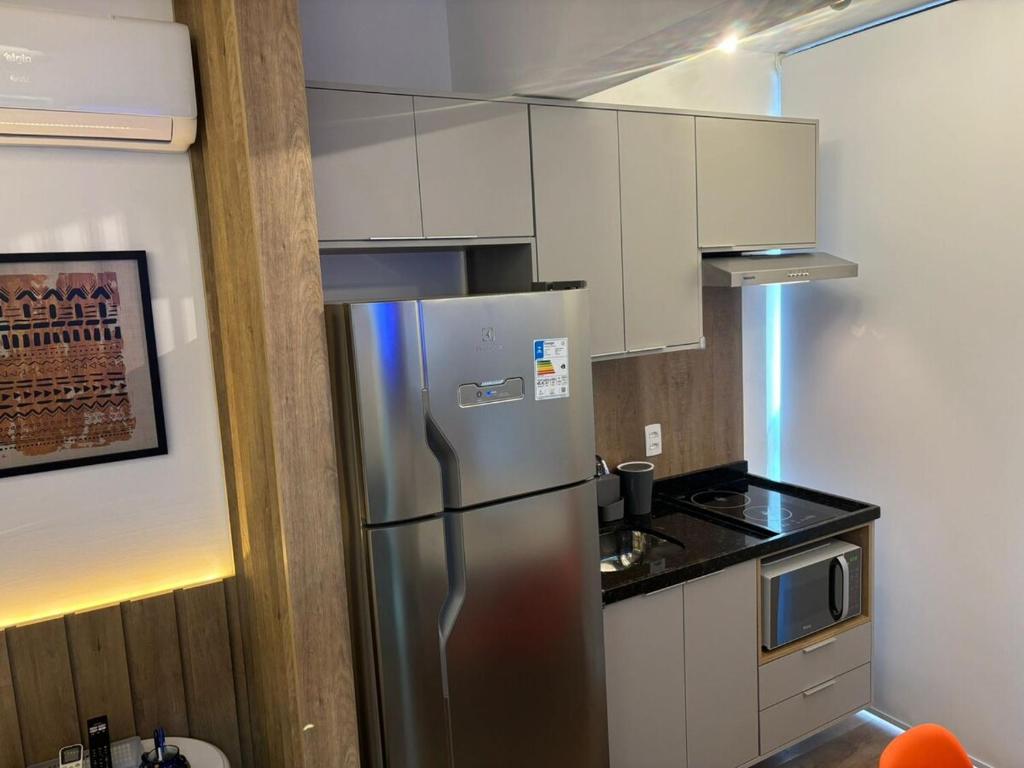 uma cozinha com um frigorífico de aço inoxidável e armários brancos em Studio São Paulo prox- PUC Allianz Park Esp Unimed 409WBE em São Paulo