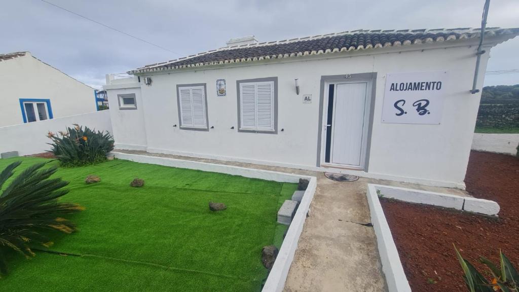 ein Haus mit einem kleinen Garten mit grünem Rasen in der Unterkunft Alojamento São Brás in São Brás