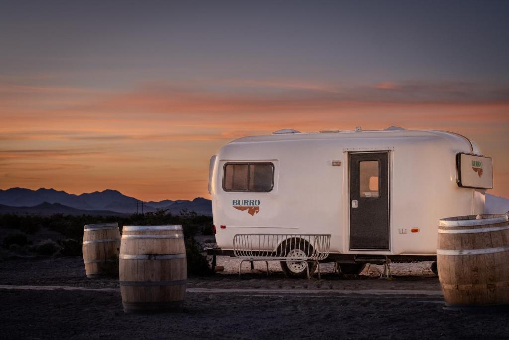 a white trailer parked in a field with barrels at Tarantula Ranch Campground & Vineyard near Death Valley National Park in Amargosa Valley