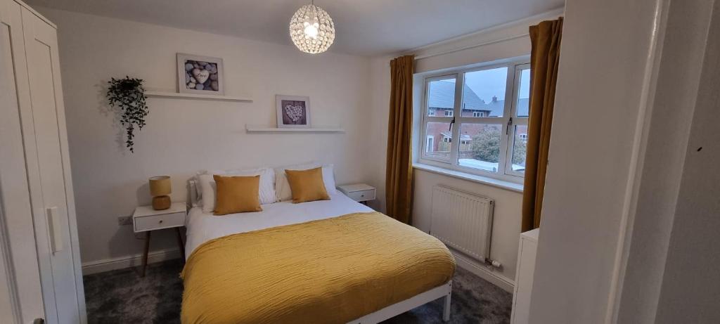 um quarto com uma cama com um cobertor amarelo e uma janela em Three Bedroom Home in Myddle em Myddle