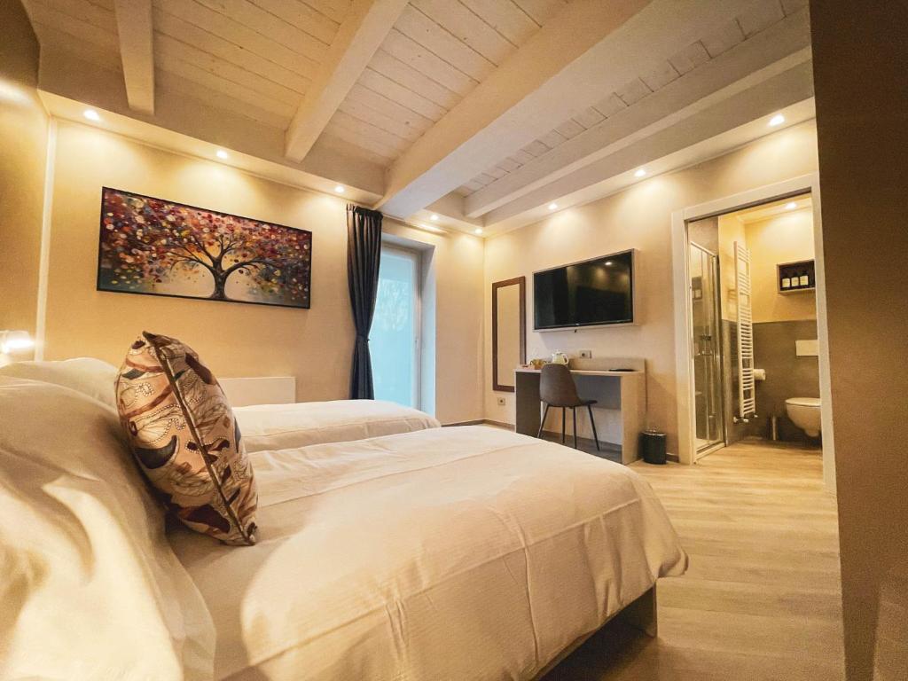 una camera con due letti bianchi e una televisione di GIO' HOUSE a Fossano