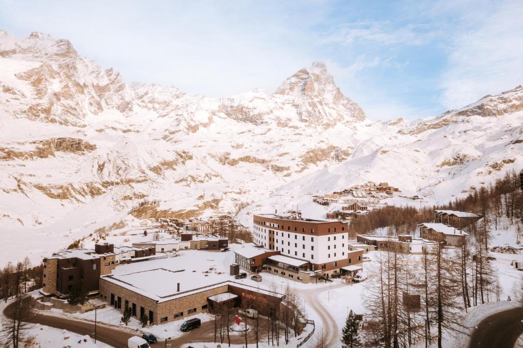 um edifício na neve com uma montanha ao fundo em Valtur Cervinia Cristallo Ski Resort em Breuil-Cervinia