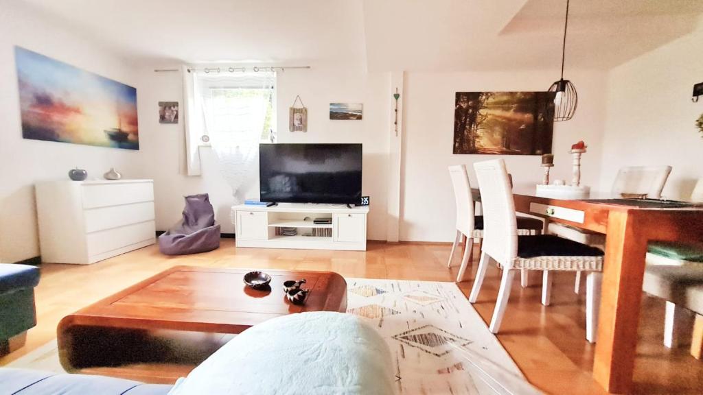 Una sala de estar con una mesa y un televisor. en Apartment Neuweiher, en Daisendorf