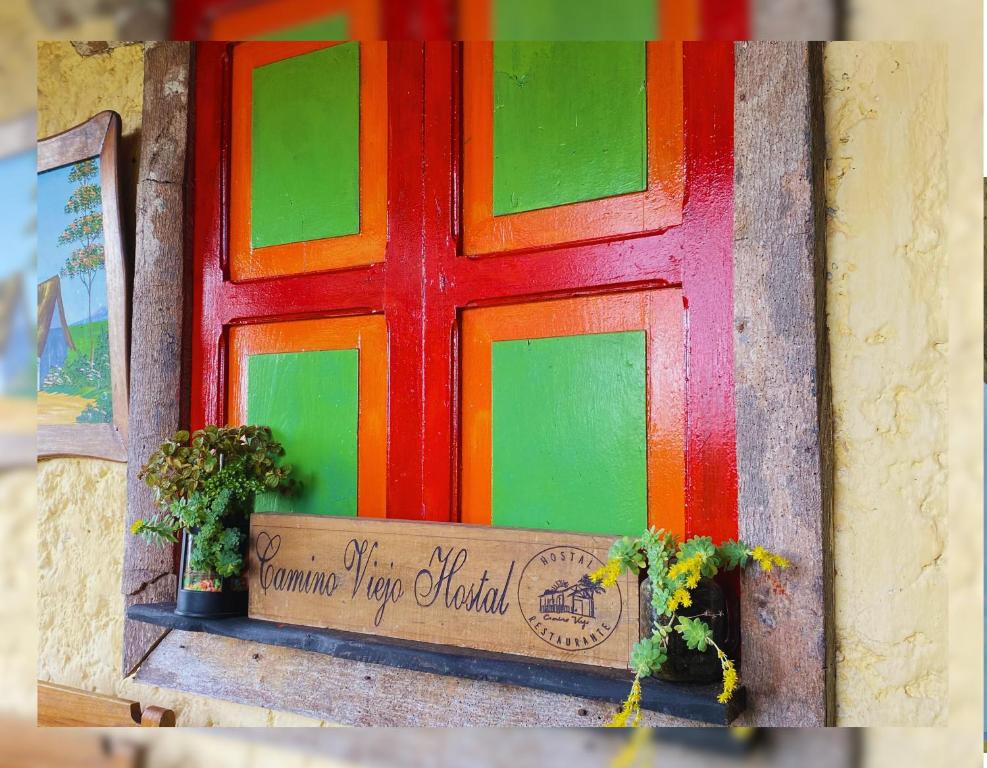 a multicolored door with two plants on a ledge at Hostal Camino Viejo in Líbano