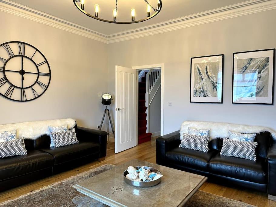 a living room with two black couches and a clock at Seaview Penthouse in Seaham