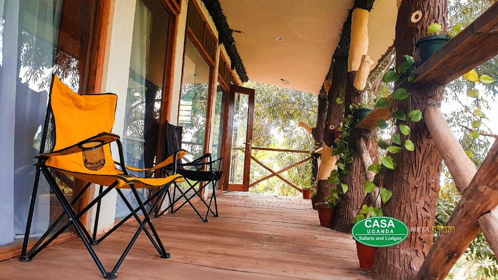 Bamasaba Community Lodge في Mbale: كرسي اصفر جالس على شرفة بجانب شجرة