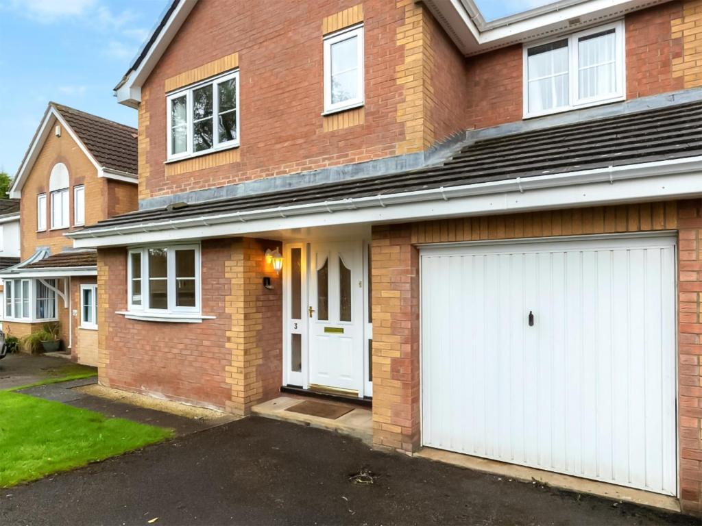 a brick house with two white garage doors at Bluebell House in Bishop Auckland