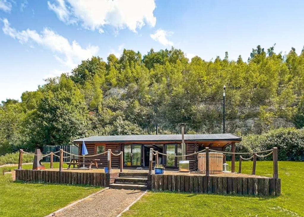 uma cabana de madeira com um parque infantil num campo em St Andrews Lakes 