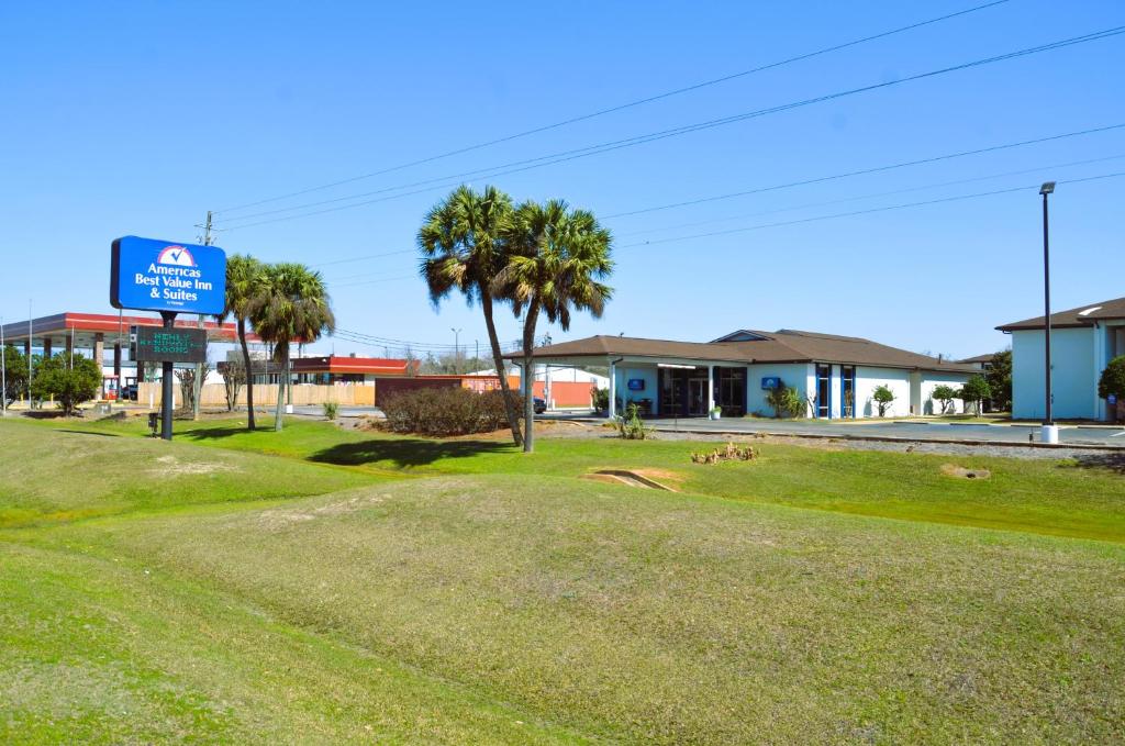 a sign on a street with palm trees and houses at Americas Best Value Inn & Suites-Foley in Foley